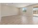 An empty living room with wood-look tile floor and a sliding glass door out to the backyard at 18351 W Patrick Ln, Surprise, AZ 85387