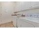 Well-lit laundry room with white cabinets, countertops, washer, and dryer for efficient household tasks at 18449 W Piedmont Rd, Goodyear, AZ 85338