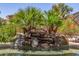 Backyard pool with rock waterfall feature surrounded by lush tropical landscaping creating a relaxing oasis at 18449 W Piedmont Rd, Goodyear, AZ 85338