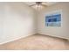 A well-lit bedroom with neutral walls and carpet, showcasing a ceiling fan and a bright window at 1865 E Locust Pl, Chandler, AZ 85286