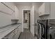 Well-organized laundry room with gray cabinets, marble counters, and modern black washer and dryer at 20452 E Appaloosa Dr, Queen Creek, AZ 85142