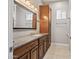 Well-lit bathroom with wooden cabinets, stone countertops, a large mirror, and updated fixtures at 24695 S 195Th Way, Queen Creek, AZ 85142