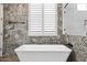 Luxurious bathroom with patterned accent wall, freestanding tub and white shutters at 24695 S 195Th Way, Queen Creek, AZ 85142
