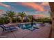 Tranquil pool surrounded by mature palm trees and a desert landscape at twilight at 24695 S 195Th Way, Queen Creek, AZ 85142