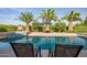 Beautiful backyard pool area with mature palm trees, lush green landscaping and seating at 24695 S 195Th Way, Queen Creek, AZ 85142