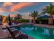 Backyard pool with a spa, palm trees, and lounge chairs at sunset at 24695 S 195Th Way, Queen Creek, AZ 85142