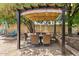Outdoor dining area featuring a shaded pergola, wicker chairs, and string lights in a lush backyard setting at 5912 E Wethersfield Rd, Scottsdale, AZ 85254