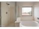 Bright bathroom features a glass-enclosed shower and separate soaking tub under a bright window at 694 W Desert Seasons Dr, San Tan Valley, AZ 85143