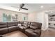 Cozy living room with an oversized leather sectional, a ceiling fan, and built-in shelving, offering comfort and style at 7502 W Cora Ln, Phoenix, AZ 85033