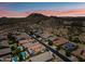 Aerial view of a neighborhood with beautiful desert landscaping and mountain views at sunset at 7939 W Fetlock Trl, Peoria, AZ 85383