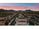 Wide aerial shot showcases a community with houses with solar panels and backyard pools against a mountain backdrop at 7939 W Fetlock Trl, Peoria, AZ 85383