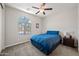 Comfortable bedroom featuring a cozy bed, a ceiling fan, and a large window with natural light at 7939 W Fetlock Trl, Peoria, AZ 85383