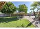 Secluded backyard with mature trees, tiki umbrellas and lush green lawn creating a private retreat at 12434 S Ki Cir, Phoenix, AZ 85044