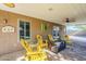 Covered patio with yellow chairs, table, a ceiling fan and access to backyard at 12434 S Ki Cir, Phoenix, AZ 85044
