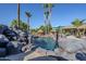 Lush tropical backyard with a sparkling pool, rock waterfall, and mature palm trees for relaxation at 12434 S Ki Cir, Phoenix, AZ 85044