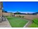 Spacious backyard with a covered patio, outdoor furniture, lush artificial turf, and a privacy wall at 13162 W Golden Puma Trl, Peoria, AZ 85383