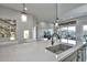 A kitchen island featuring a stainless steel sink, seating, pendant lighting, and an open view to the living area at 13162 W Golden Puma Trl, Peoria, AZ 85383
