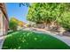 Expansive backyard featuring green turf, a stone fire pit, water fountain and mature landscaping at 1807 W Canary Way, Chandler, AZ 85286