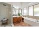 Bright bathroom with a glass shower, wood vanity, and a luxurious bathtub under translucent windows at 1807 W Canary Way, Chandler, AZ 85286
