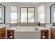 Bright bathroom featuring a luxurious soaking tub under translucent windows, with a wood vanity on each side at 1807 W Canary Way, Chandler, AZ 85286