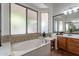 Bright bathroom featuring a soaking tub under translucent windows, with a wood vanity and large mirror at 1807 W Canary Way, Chandler, AZ 85286