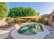 Gorgeous swimming pool surrounded by lush landscaping, a sunshade, and beautiful stonework, perfect for outdoor relaxation at 1807 W Canary Way, Chandler, AZ 85286