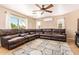 Spacious living room with a comfortable brown leather sectional, large windows, and ceiling fan at 1991 S Bahama Dr, Gilbert, AZ 85295