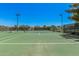 View of well-maintained tennis courts with green surface, surrounding fencing and lights for evening play at 1991 S Bahama Dr, Gilbert, AZ 85295