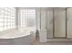 Bright bathroom featuring a soaking tub beneath a unique glass block window and glass-enclosed shower at 2230 E Whitten St, Chandler, AZ 85225