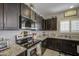 Modern kitchen with stainless steel appliances, granite countertops, and dark cabinets at 23781 W Mohave St, Buckeye, AZ 85326