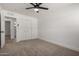 Well-lit bedroom with gray carpet and ceiling fan also offers closet and access to the en-suite bathroom at 3021 E Windrose Dr, Phoenix, AZ 85032