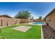 Landscaped backyard featuring a refreshing pool, artificial grass, and a brick patio at 308 W Oraibi Dr, Phoenix, AZ 85027