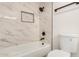 Modern bathroom features a sleek white tub with shower, matching tile, and updated fixtures at 308 W Oraibi Dr, Phoenix, AZ 85027