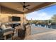 Luxurious outdoor living space features a covered patio, comfortable seating, tv, and a sparkling pool at 31210 N 122Nd Ln, Peoria, AZ 85383