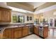 Well-lit kitchen featuring stainless steel appliances, wood cabinetry, stone countertops, and tile flooring at 4136 E Greenway Cir, Mesa, AZ 85205