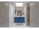 Bright bathroom with a blue vanity, tiled walls, and a skylight for natural illumination at 4918 N 74Th St, Scottsdale, AZ 85251