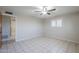 Comfortable bedroom featuring tile flooring, a ceiling fan, and shutters, leading to bathroom at 5618 E Des Moines St, Mesa, AZ 85205