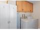 Practical laundry room features storage, an ironing board, and white washer and dryer for convenience at 636 S Rosemont --, Mesa, AZ 85206