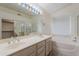 Bathroom featuring double sink vanity, large mirror, soaking tub, and glass enclosed shower at 7345 E Forge Ave, Mesa, AZ 85208