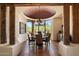 A dining room features a round wooden table, seating for six, decorative chandelier, and large windows at 7731 E Soaring Eagle Way, Scottsdale, AZ 85266
