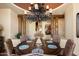 A dining room features a round wooden table set with placemats, upholstered chairs, and a decorative chandelier at 7731 E Soaring Eagle Way, Scottsdale, AZ 85266