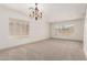 Spacious, carpeted living room with chandelier and ample natural light from large windows at 82 N 221St Ave, Buckeye, AZ 85326