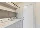 Bright laundry room with white washer and dryer and shelving for storage space at 8540 W Ocotillo Rd, Glendale, AZ 85305