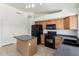 Kitchen features an eat-in island, wood cabinets, black appliances, tile flooring and track lighting at 16783 W Taylor St, Goodyear, AZ 85338
