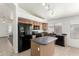 Kitchen showcasing an eat-in island, wood cabinets, black appliances, tile flooring and track lighting at 16783 W Taylor St, Goodyear, AZ 85338