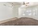 Open-concept living room featuring tile and carpet flooring, ceiling fan, and natural light at 16783 W Taylor St, Goodyear, AZ 85338