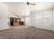Inviting living room showcases natural light, opening into the kitchen with black appliances and carpet flooring at 16783 W Taylor St, Goodyear, AZ 85338