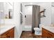 Bathroom with double sink vanity, a toilet, bathtub/shower with curtain, and a framed mirror at 18455 W San Carlos Dr, Goodyear, AZ 85338