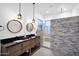 Modern bathroom with a double sink vanity, round mirrors, and a walk-in shower with gray stone accent wall at 18455 W San Carlos Dr, Goodyear, AZ 85338