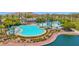 Beautiful community pool with a slide and lounge chairs with lake views and lush landscaping at 18455 W San Carlos Dr, Goodyear, AZ 85338
